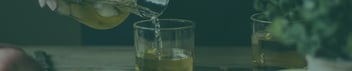 Servir sidra dorada en un vaso sobre una mesa rústica.