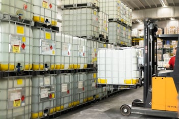 Warehouse with forklift transporting large containers of neutral alcohol and industrial ethanol.