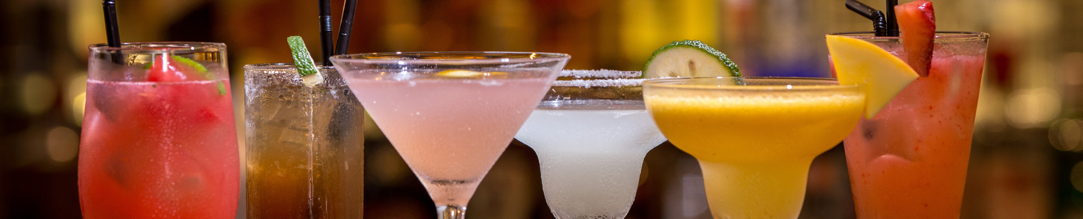  Colourful cocktail lineup featuring various spirits-based drinks, capturing beverage trends for 2026 with garnishes like lime, lemon, and strawberry. 