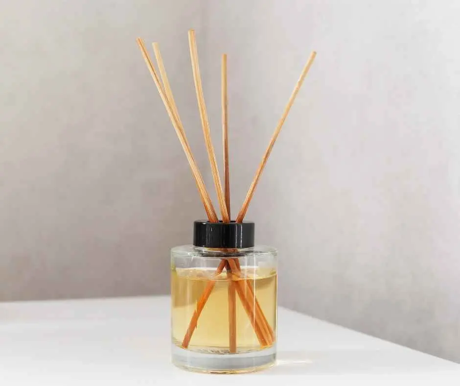 Reed diffuser filled with alcohol-based fragrance for home scenting, placed on a shelf.